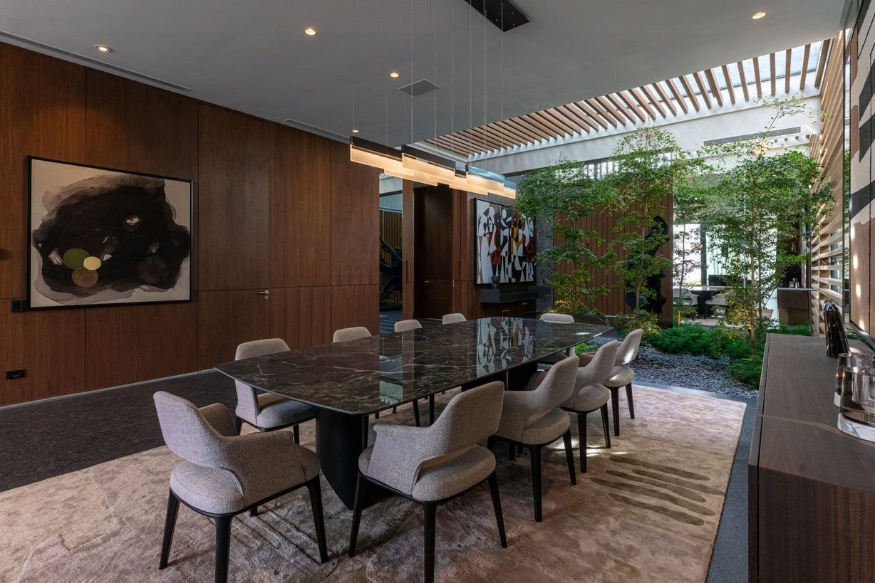 Fotografía inmobiliaria de comedor con muros de madera y jardín interior en Monterrey